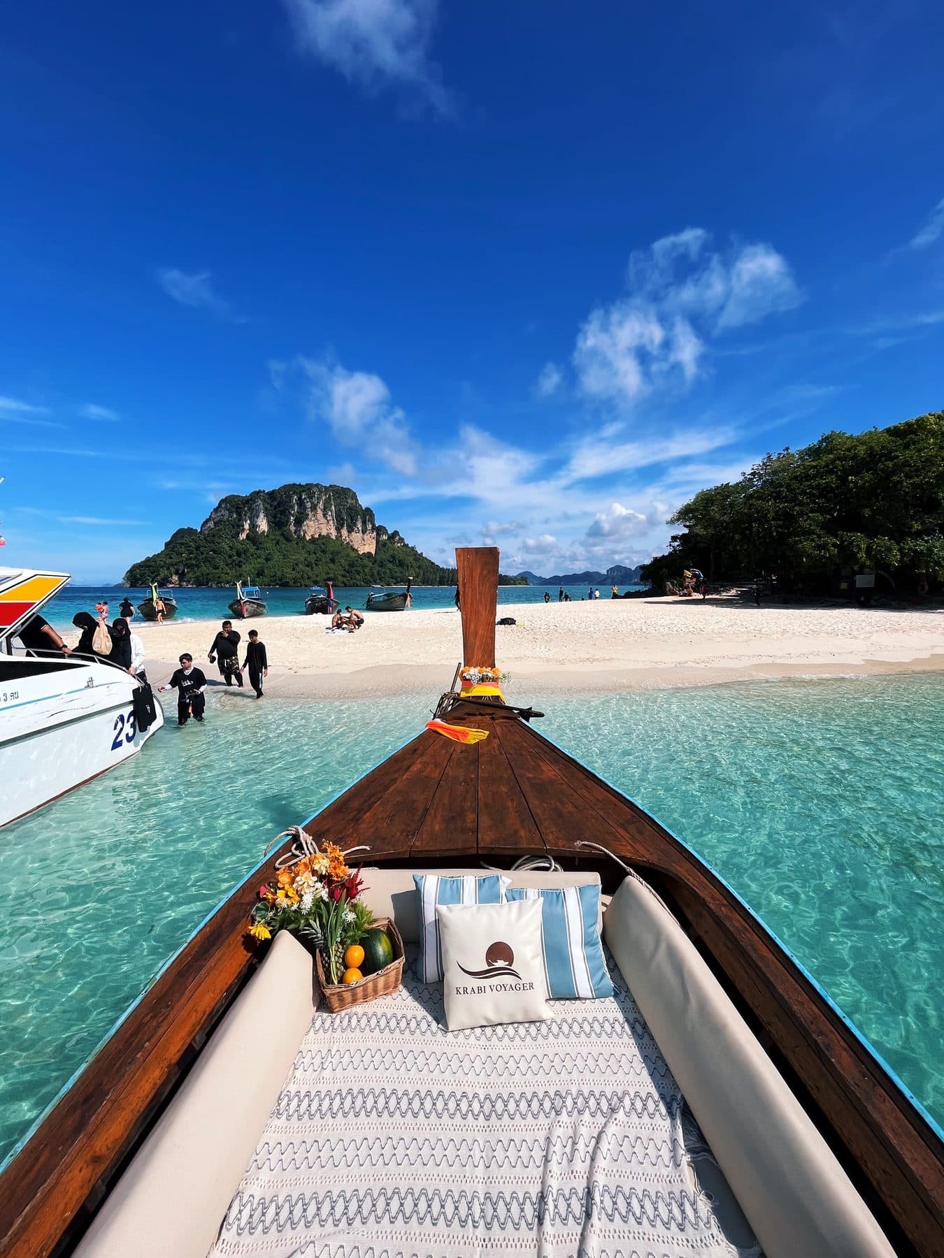View from the bow with cushions and a fruit basket, arriving at a white-sand island