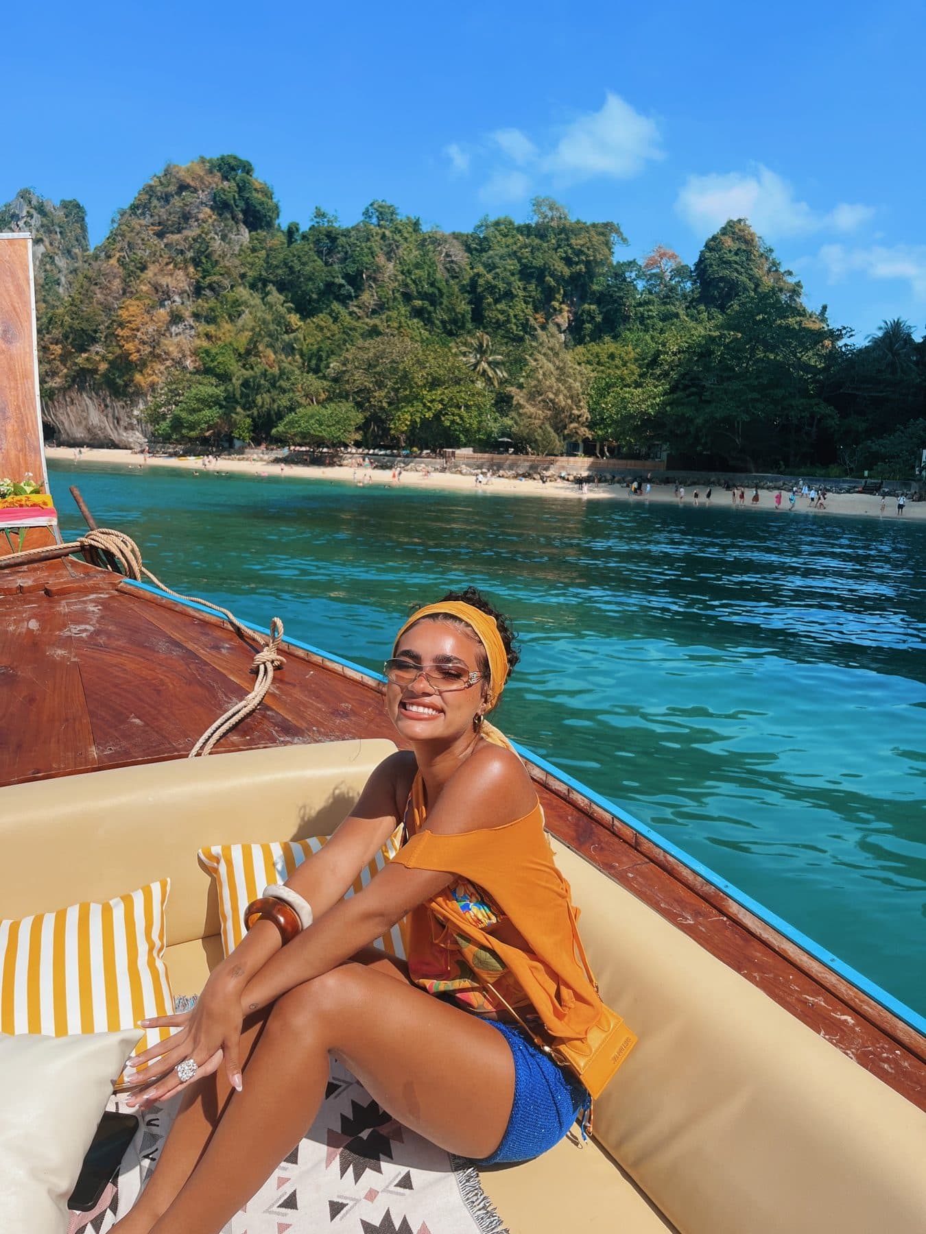 Guest smiling on board with a beach and limestone cliffs behind