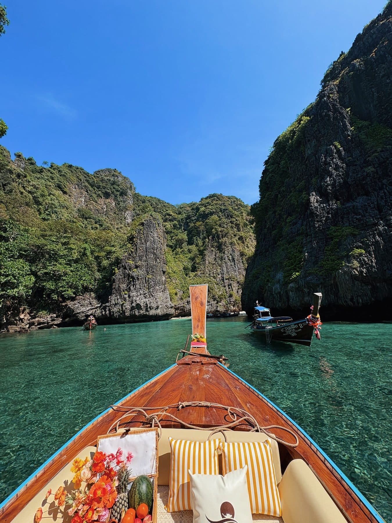 Proue d’un longtail entrant dans un lagon entouré de hautes falaises