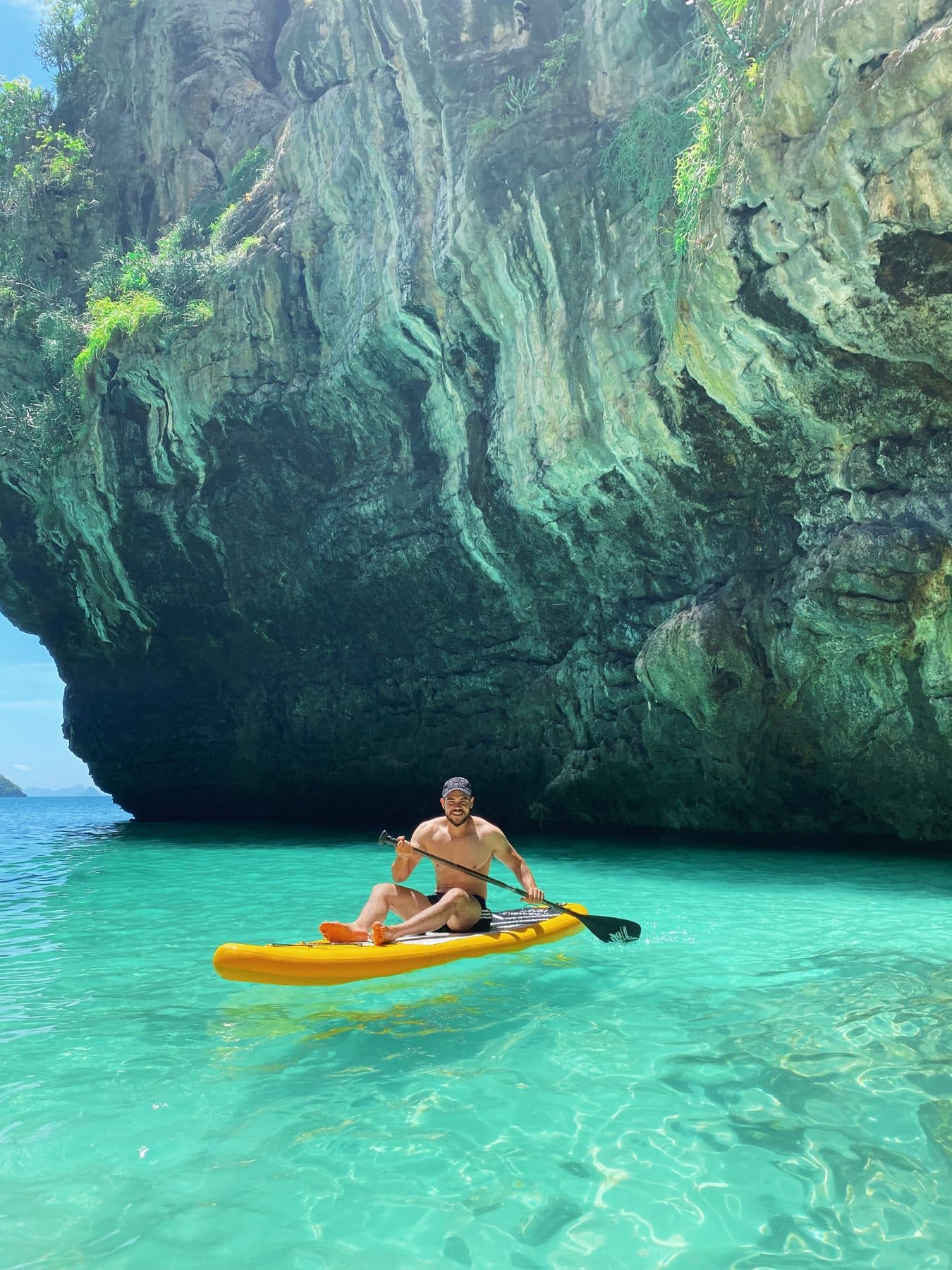 Guest on a paddle board beneath a limestone overhang